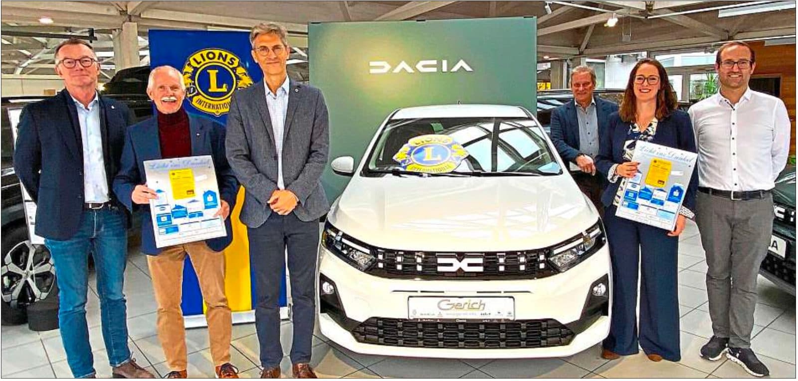 6 Personen vor einem weißen Auto mit Lions-Logo.